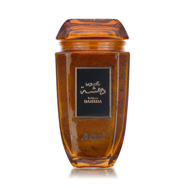 A glass jar with a brown liquid inside, presumably the Dahsha Bakhoor, with a black label on the front and a wooden lid on top.
